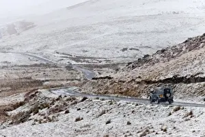 Powys Prints: A four wheel drive vehicle negotiates a road through a wintry landscape in the Elan