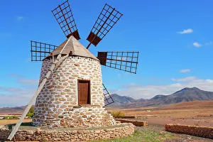 Energy Prints: Windmill structure on Fuerteventura in the Canary Islands with blue sky and mountains in the background