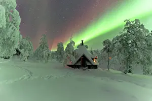 Muonio Prints: Winter frame of a hut lit by the green Northern Lights (Aurora Borealis) in the icy wood with trees covered with snow