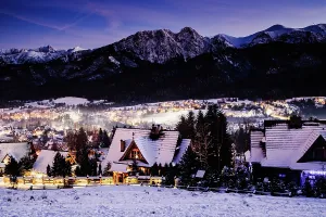 Nighttime Prints: Winter night view of Zakopane and the High Tatras in Poland with snow-covered rooftops and mountain peaks