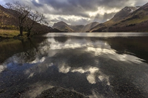 Winter reflections, shafts of sunlight break through clouds, Buttermere, Lake District