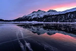 Engadine Prints: Winter sunrise on snowcapped mountains mirrored in the icy Lake Silvaplana, Maloja