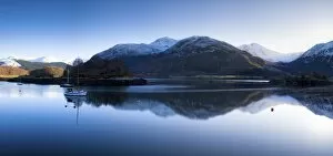Winter view of flat calm Loch Leven with snow covered mountains reflected