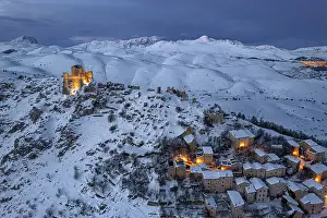 Rocca Calascio Prints: Winter view of the snow covered illuminated medieval village of Rocca Calascio with the castle at dusk