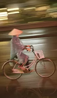 Woman on bicycle in rain, Vietnam, Indochina, Southeast Asia, Asia