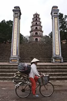 Woman on bicycle in front of Thien Mu Pagoda, Hue, Vietnam, Indochina, Southeast Asia