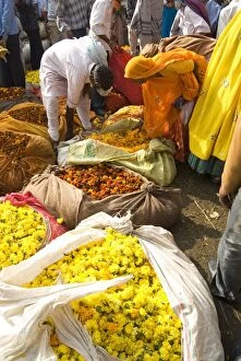Woman buying marigolds tied up in cloth and sacking, flower market, Bari Chaupar