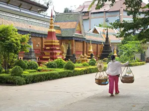 Carrying Prints: Woman carrying baskets over her shoulders outside a temple in Siem Reap, Cambodia
