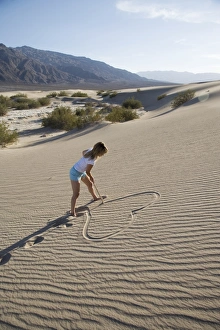 Love Prints: Woman drawing a heart in the sand