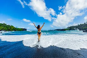 Woman enjoying the sun on one of Mauis black sand beaches, Maui, Hawaii