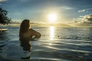 Papeete Prints: Woman enjoying the sunset in a swimming pool with Moorea in the background, Papeete
