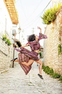 Albania Prints: Woman jumping on the street in Berat, Albania, Europe