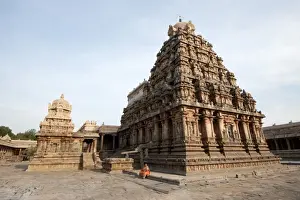 Woman in orange sari sitting beside the vimala section of Swaminathaswamy temple
