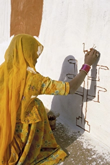 Obscured Face Prints: Woman painting design on a wall in a village near Jaisalmer