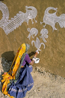 Obscured Face Prints: Woman painting designs on her house