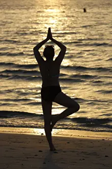 40 To 45 Prints: Woman practising yoga meditation on beach at sunset as concept for silence and relaxation