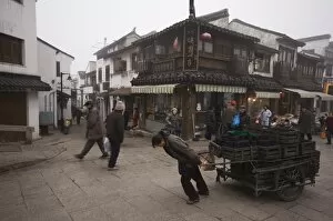 A woman pulling a cart of charcoal bricks on an old street in Shantang district of Suzhou
