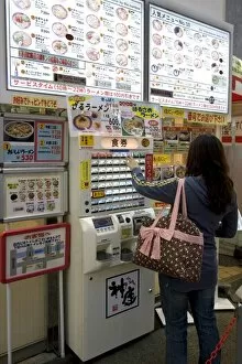 Woman purchasing meal tickets from a vending machine at a restaurant in Dotonbori