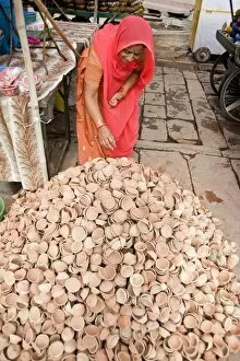 Images Dated 13th October 2009: Woman in red sari with pile of terracotta deepak candle dishes for Diwali festival celebrations