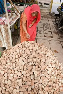 Terra Cotta Prints: Woman in red sari with pile of terracotta deepak candle dishes for Diwali festival celebrations
