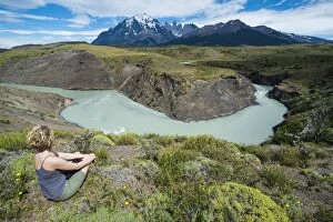 Woman sitting above a river bend in front of the Torres del Paine National Park, Patagonia, Chile, South America