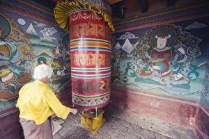 Images Dated 5th October 2009: A woman spinning a prayer wheel, Chimi Lhakhang dating from 1499