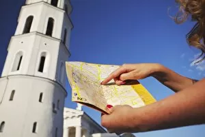 Woman standing outside Vilnius Cathedral Belfry with map, Vilnius, Lithuania