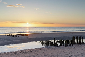 Evening Light Prints: Woman standing next to wooden groynes on Rantum beach at sunset