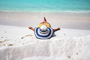 Enjoying Prints: Woman with straw hat sunbathing on tropical beach, The Maldives, Indian Ocean