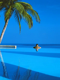 Images Dated 24th April 2008: Woman in swimming pool under palm tree looking at sea, Maldives, Indian Ocean, Asia