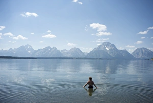 Wade Prints: Woman wades in lake with Tetons in distance, Grand Teton National Park