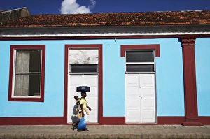 Single Storey Prints: Woman walking past colourful house, Inhambane, Mozambique, Africa