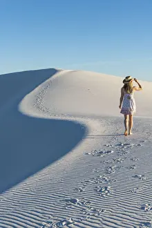 35 To 39 Years Prints: A woman walking along thes curve of a dunes ridge in White Sands National Park