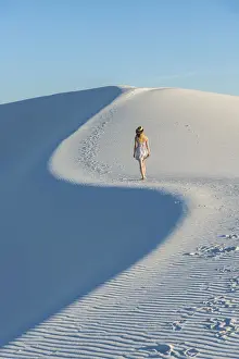 A woman walking along thes curve of a dunes ridge in White Sands National Park