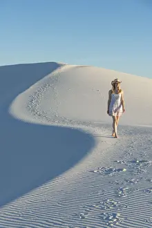 A woman walking along thes curve of a dunes ridge in White Sands National Park