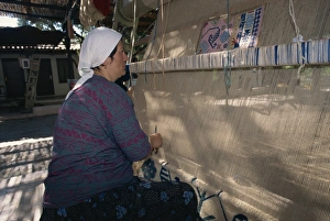 Carpet Prints: Woman weaving wool carpet on a loom in a workshop at Kusadasi