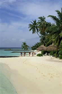 Women on the beach with thatched umbrellas and palm