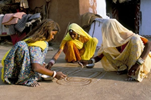 Women painting a mandana on the ground