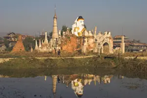 Women walking past huge sitting Buddha said to be 700 years old, at Kyaukh-pyugyi Paya