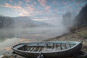Wood boat on the shore of River Mera at sunrise, Sorico, Como province, Lower Valtellina