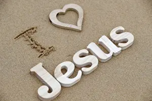 Jesus Christ Prints: Wooden letters forming the word JESUS with heart on a background of beach sand