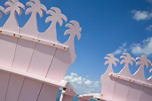 Detail of wooden pink beach chairs with backs carved in the shape of palm trees