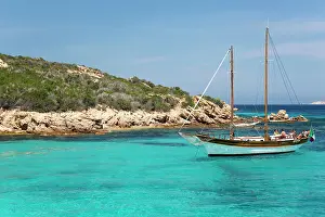 Azure Waters Prints: Wooden sailing boat anchored in clear turquoise water off Cala Granara