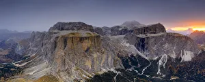 Woods in autumn at foot of Sass Pordoi and Sella mountain at dawn, aerial view