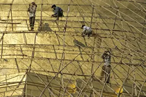 Workers on bamboo scaffolding applying fresh gold leaf to the Shwedagon Pagoda