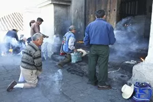 Worshippers praying and burning incense on the steps of Iglesia De Santo Tomas