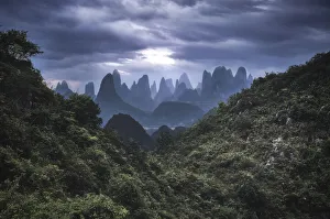 Guangxi Prints: Yangshuo mountains with dark clouds framed by hills, Yangshuo, Guangxi, China, Asia
