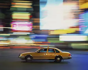 Cabs Prints: Yellow cab driving past blurred neon lights at night in Times Square in New York