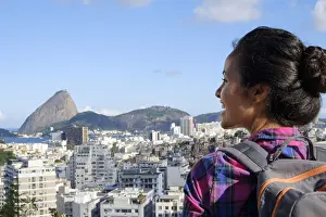 Looking At View Prints: Young backpacker on her mobile phone in central Rio de Janeiro with the Sugar Loaf in the distance