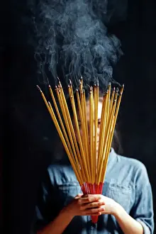 Adults Prints: Young Chinese woman praying with big burning incense sticks in her hands